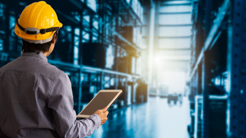 Supply chain manager holding a tablet looking over a warehouse