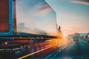 Truck driving on a motorway with a sunset in the background