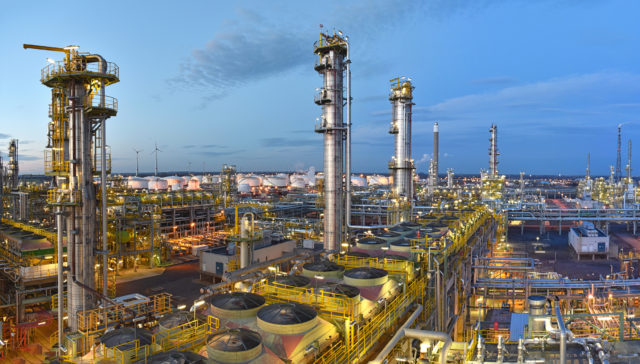 refinery - chemical factory at night with buildings, pipelines and lighting - industrial plant